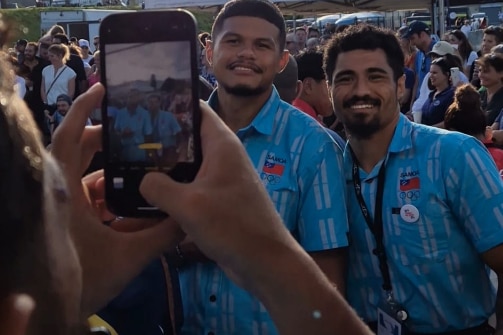 Manu Samoa 7s players in blue patterned button up shirts have their picture taken by a supporter or fan 