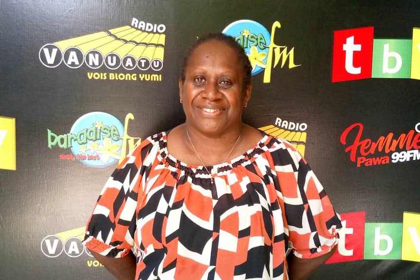 niVanuatu woman Christina Thyna standing in front of a a Radio Vanuatu banner